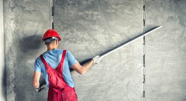 industrial worker with plastering tools renovating a house. builder worker plastering facade industrial building with leveler